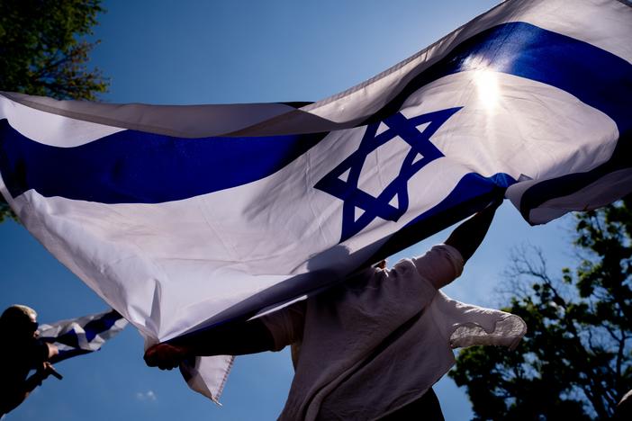 People dance and wave large Israeli flags during a rally against campus antisemitism at George Washington University in May 2024 in Washington, D.C.