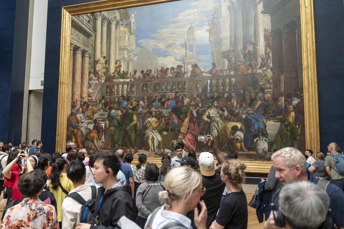 Louvre visitors in front of <em>The Wedding Feast at Cana</em> by Paolo Veronese in June 2024. The painting is among several masterworks that may soon cease to play "second fiddle'" to the Mona Lisa.