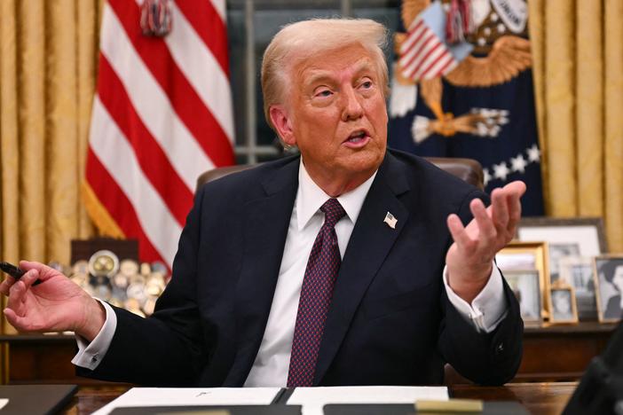 President Trump speaks to journalists as he signs an executive order regarding Department of Government Efficiency (DOGE), in the Oval Office of the White House on Jan. 20.