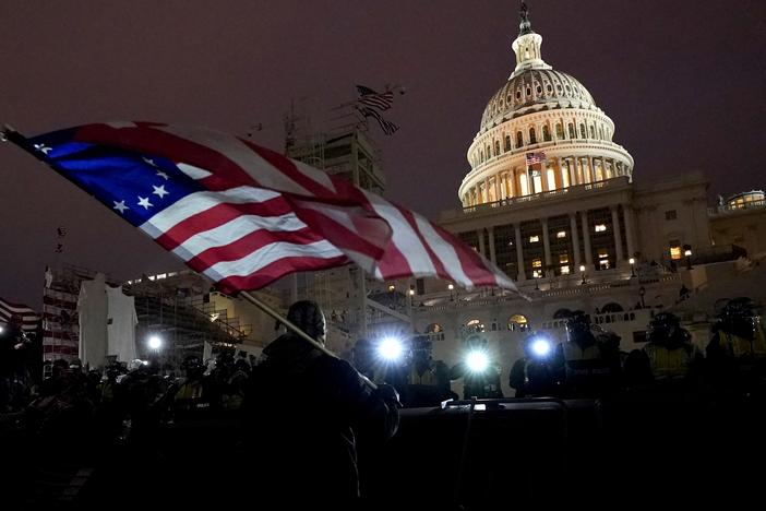 Protesters hold flags as they are pushed back by police on Jan. 6, 2021, after President Trump's supporters stormed the U.S. Capitol. Trump pardoned almost every person who participated in the riot.