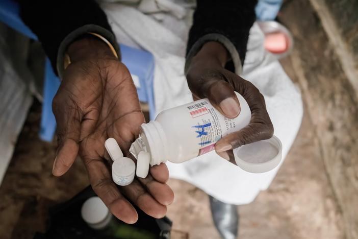 A woman in Nairobi, Kenya, who is HIV positive takes antiretroviral pills, which suppress the virus. The U.S. program PEPFAR is instrumental in providing these life-saving medications around the world.
