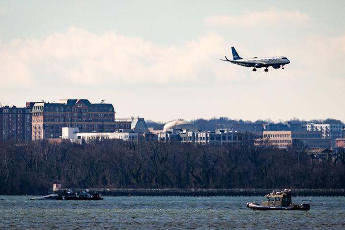 A flight flies over law enforcement boats and the partially submerged fuselage of American Airlines Flight 5342 in the Potomac River on Saturday in Washington, D.C.