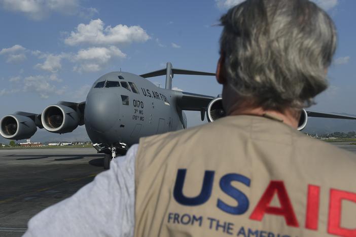 A USAID officer watches as a US military C-17 cargo plane taxis to a stop at Kathmandu's international airport on May 3, 2015.  International aid continues to pour into Nepal to help victims of a massive earthquake on April 25 killed at least 7,200 people and devastated vast swathes of one of Asia's poorest countries.
