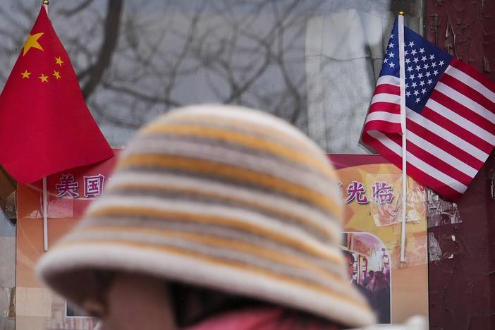 A woman walks by the Chinese and U.S. national flags on display outside a souvenir shop in Beijing on Jan. 31, 2025.