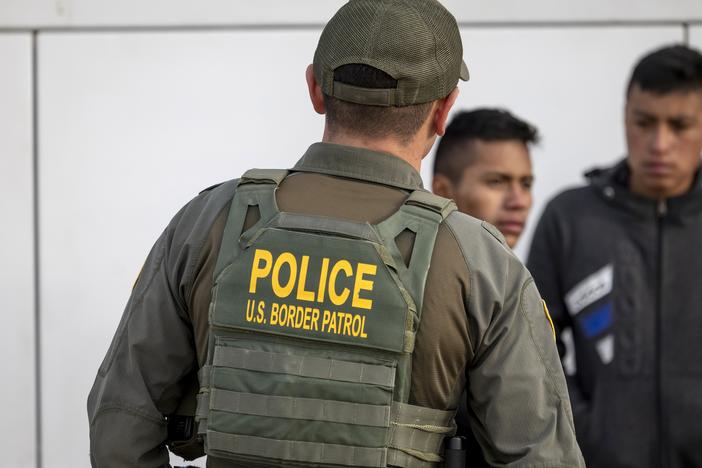 A U.S. Border Patrol agent watches as immigrants prepare to board a bus after crossing the U.S.-Mexico border on Jan. 7, 2024 in Eagle Pass, Texas.