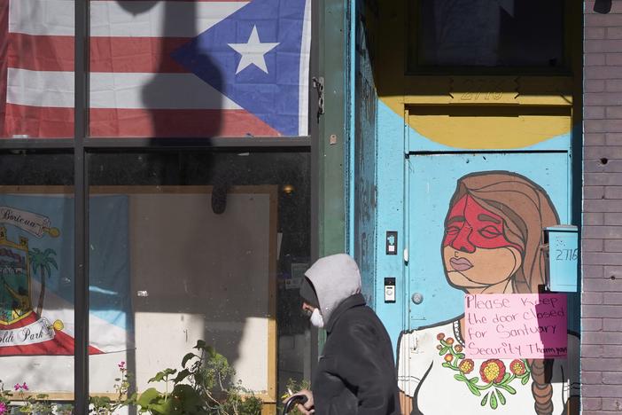 A pedestrian walks past the flag of Puerto Rico and the colorful door to the sanctuary apartment of Chicago's Adalberto Memorial United Methodist Church in Chicago in 2021. The church has provided shelter to immigrants in the U.S. illegally.