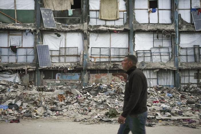 A man walks past a house that remains partly standing, but with sheets serving as makeshift walls and solar panels partly working, in an area largely destroyed by the Israeli army's air and ground offensive in Gaza City on Wednesday.