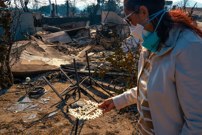 Margaret Larkin holds a piece of her Christmas decor outside of what remains of her home. Larkin lived on her block in Altadena, Calif. for 36 years.