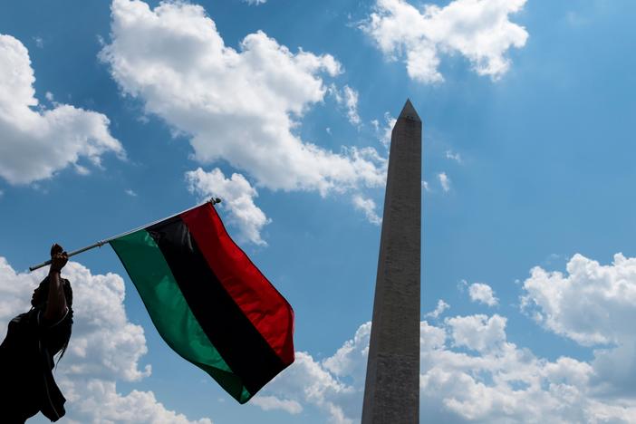 A woman waves a Pan-African flag next to the Washington Memorial in Washington, D.C.