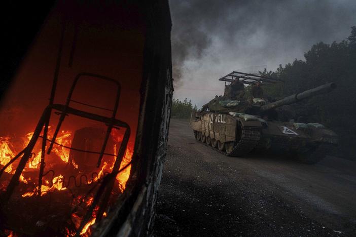 A Ukrainian tank passes by a burning car near the Russian-Ukrainian border, Sumy region, Ukraine, on Aug. 14, 2024.