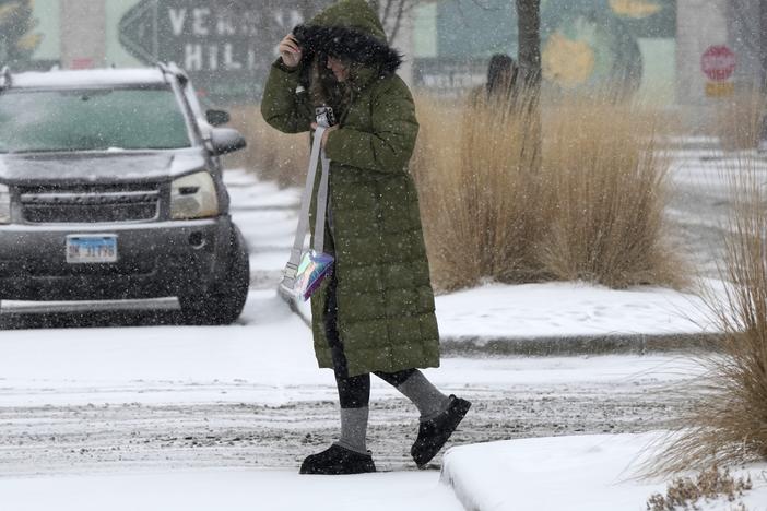 Pedestrian crosses the street during a snowy day in Vernon Hills, Ill., Wednesday.
