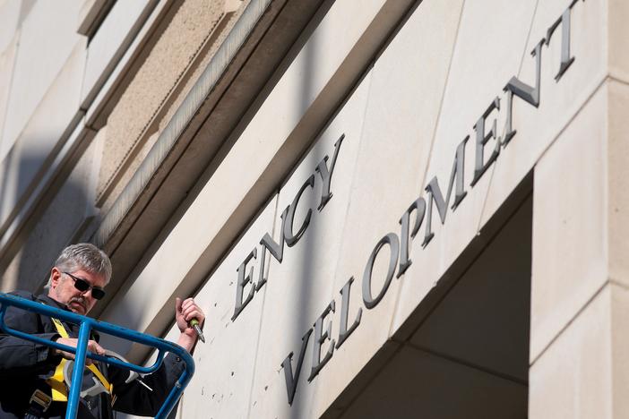 A worker removes the U.S. Agency for International Development sign on their headquarters on February 7. A judge is set to extend the pause of President Donald Trump's plan to put employees on administrative leave.