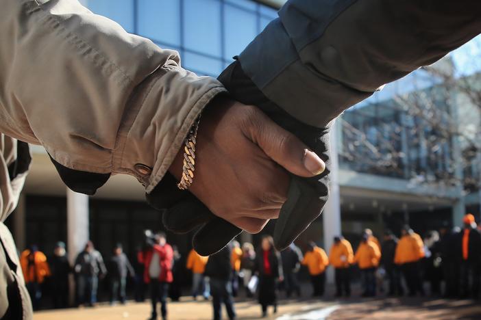Students and community leaders pray outside a Chicago High School in the aftermath of a student's death from gun violence.