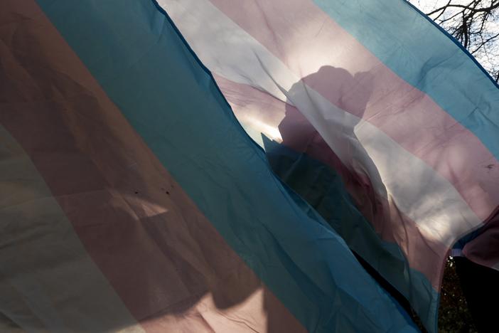 A protester is silhouetted against a trans pride flag during a pro-transgender rights protest outside of Seattle Children's Hospital, in Seattle, on Feb. 9.