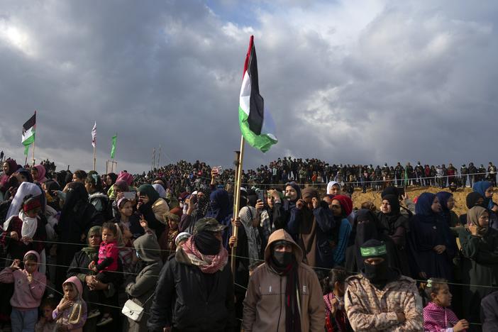 Palestinians gather as Hamas fighters deploy ahead of handing over the bodies of four Israeli hostages, including a mother and her two children, who had long been feared dead, to the Red Cross in Khan Younis, southern Gaza Strip on Thursday.