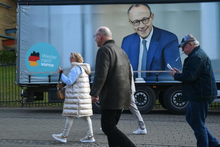 People walk past a truck with an election campaign poster featuring Friedrich Merz, leader of conservative Christian Democratic Union (CDU), in Oberhausen, Germany, on Feb. 21.