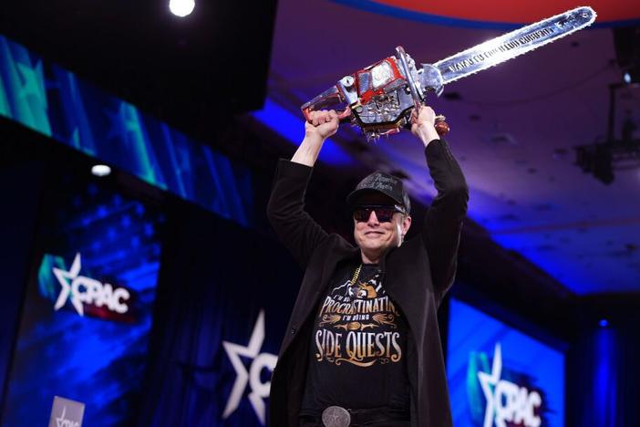 Elon Musk holds a chainsaw that was gifted to him at the Conservative Political Action Conference at the Gaylord National Resort Hotel And Convention Center on Thursday in Oxon Hill, Md.