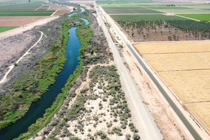 An aerial view shows the long-depleted Colorado River (L) as it flows between California (R) and Arizona, and an irrigation ditch (R) carrying river water toward Quechan tribal land on May 26, 2023 near Winterhaven, Calif.