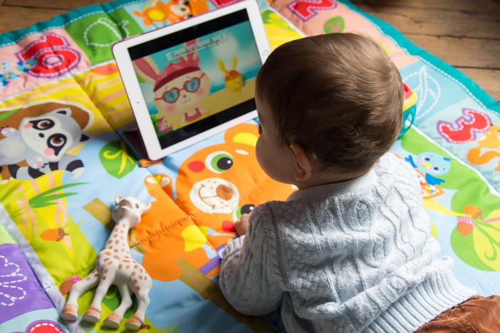 An 8-month-old baby watches a cartoon on a tablet. A survey by Common Sense Media found that 80% of parents are worried about their children spending too much time on screens.