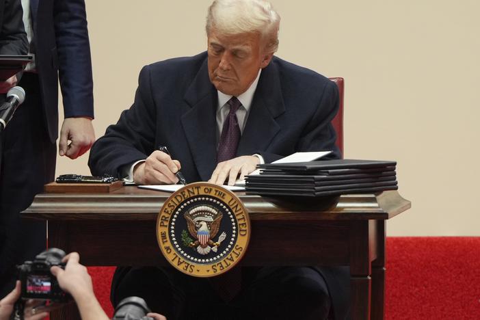 President Donald Trump signs an executive order at an indoor Presidential Inauguration parade event in Washington, Jan. 20, 2025.