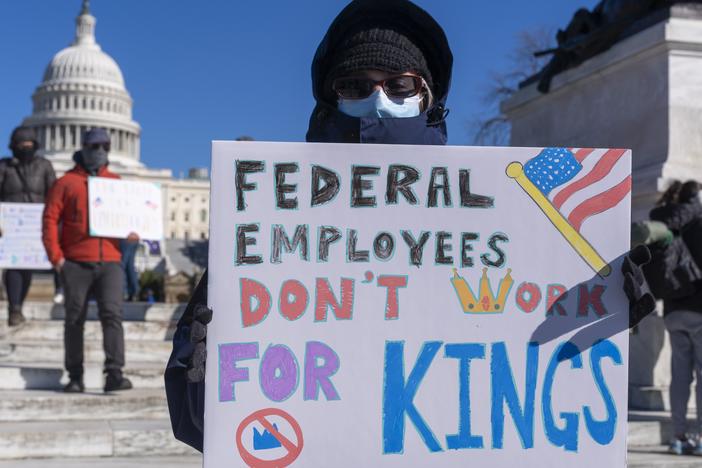 A protester with a sign saying "Federal Employees Don't Work for Kings" demonstrates in support of federal workers and against recent actions by President Trump and Elon Musk on Presidents Day in Washington, D.C.