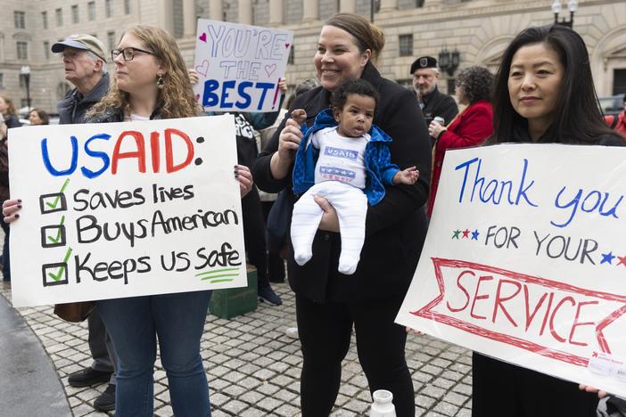 United States Agency for International Development (USAID) supporters hold banners as USAID workers retrieve their personal belongings from the USAID's headquarters in Washington, Thursday, Feb. 27, 2025.