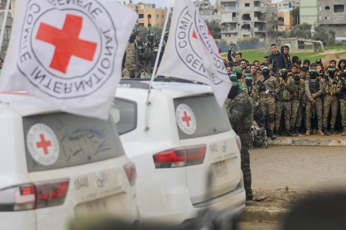 Hamas fighters stand guard as an International Red Cross vehicle arrives at the site of the handing over of two Israeli hostages in Rafah in the southern Gaza Strip, as part of the seventh hostage-prisoner release on February 22, 2025.