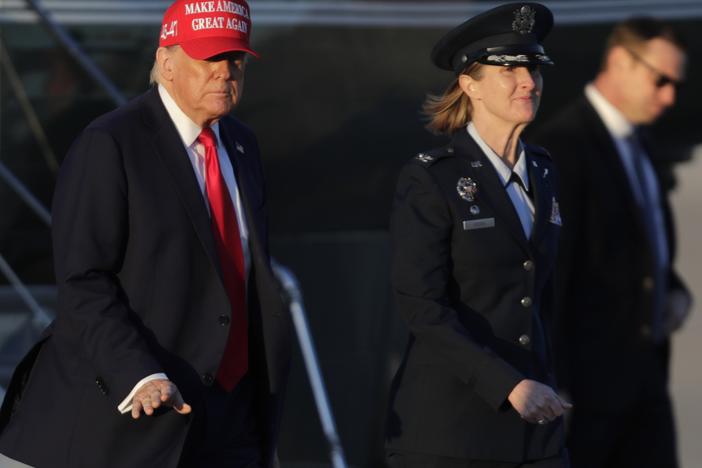 President Donald Trump, left, gestures as is escorted by Air Force Col. Angela Ochoa, commander of the 89th Airlift Wing, center, as he walks from Marine One before boarding Air Force One, Friday, Feb. 28, 2025, at Joint Base Andrews, Md.