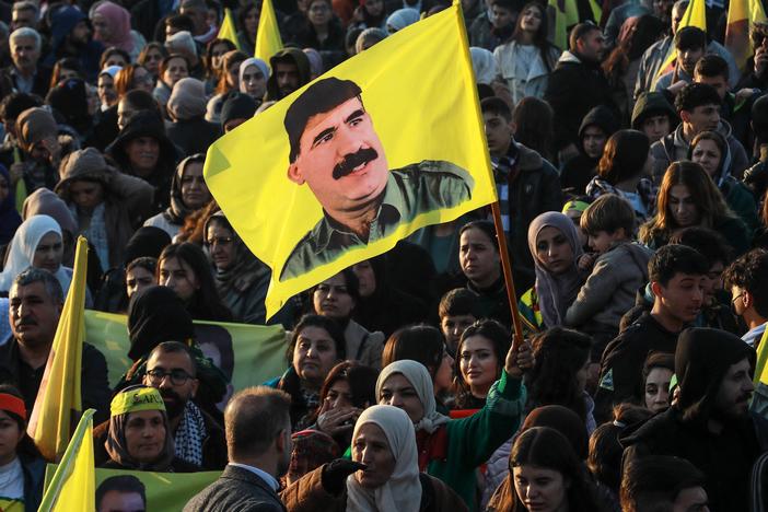 A woman waves a flag bearing a picture of the founder of the Kurdistan Workers' Party (PKK) Abdullah Ocalan, as people gather in the Kurdish-majority city of Qamishli in northeastern Syria to listen to a message from the jailed leader on Feb. 27. Ocalan called for his Kurdish militant force to disband and his fighters to lay down their arms.