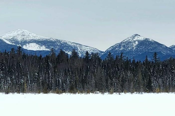 A snowshoe trek to Wolf Pond in New York's Adirondack Mountains.  After breaking trail through the woods, the icy lake opens up to views of the High Peaks Wilderness.