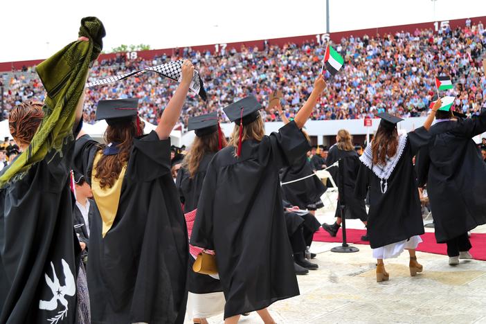 Pro-Palestinian students hold up Palestinian flags during UMass Amherst graduation ceremonies in May 2024. They left the graduation event in protest.