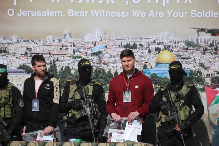 Israeli-Russian hostage Sasha Trupanov (second right) and fellow captive, Israeli-American Sagui Dekel-Chen (second left), stand on stage next to Palestinian militants during their handover to a Red Cross team in Khan Younis, in the southern Gaza Strip, on Feb. 15, as part of the sixth hostage-prisoner exchange between Israel and Hamas. Hamas says it has held direct talks with the U.S. about hostages.