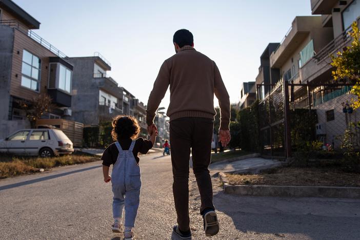 A former employee of Afghanistan's Defense Ministry walks in his neighborhood with his youngest daughter on Jan. 21, in Islamabad, Pakistan.