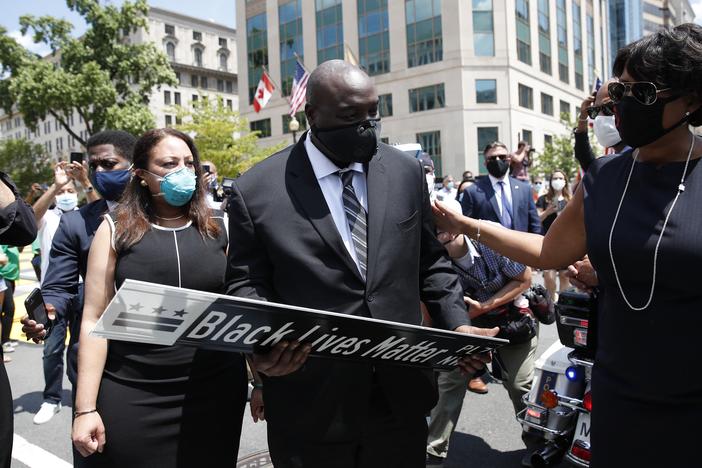 District of Columbia Mayor Muriel Bowser (R) presents a Black Lives Matter Plaza street sign to a representative of the family as the hearse with the flag-draped casket of U.S. congressman and civil rights icon John Lewis drives on 16th Street, renamed Black Lives Matter Plaza, near the White House in Washington, DC July 27, 2020.
