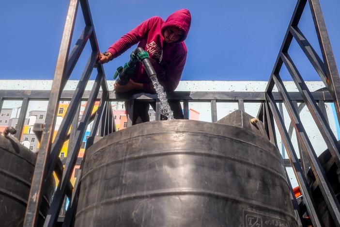 A man fills up a cistern on the back of a truck with water at the Southern Gaza Desalination plant, which stopped working earlier after Israel cut off electricity supply to the Gaza Strip on Sunday. The plant will have to work on generators now in an area where fuel is in very short supply.