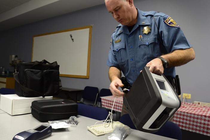 Colorado State Trooper Ron Krasnisky shows the department's oral fluid drug screen testing device, used during a pilot program that ended earlier this year. The system uses a saliva collection device to test impaired drivers for marijuana use as well as other drugs.