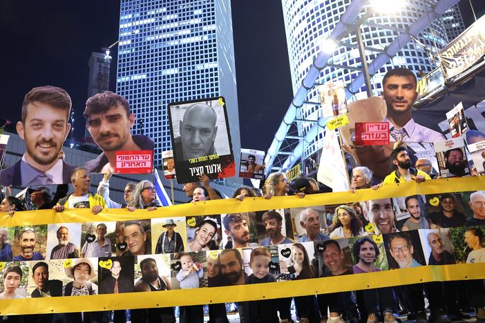 Friends and relatives of Israeli hostages held captive since the October 7, 2023 attacks by Palestinian militants in the Gaza Strip, stand behind a banner bearing their portraits during a demonstration calling for action to secure their release in front of the Israeli Defense Ministry in Tel Aviv on Tuesday.