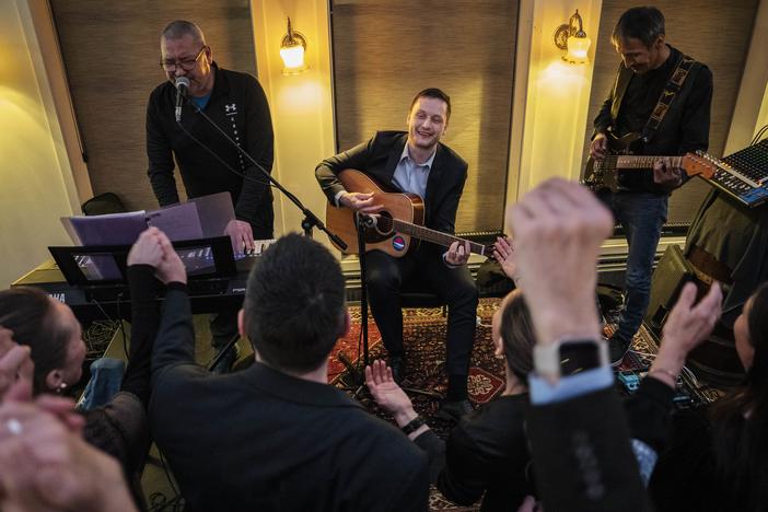 Jens-Frederik Nielsen, center, chairman of Demokraatit Party, plays guitar as he reacts during the election party at Demokraatit by cafe Killut in Nuuk, early Wednesday, March 12, 2025.