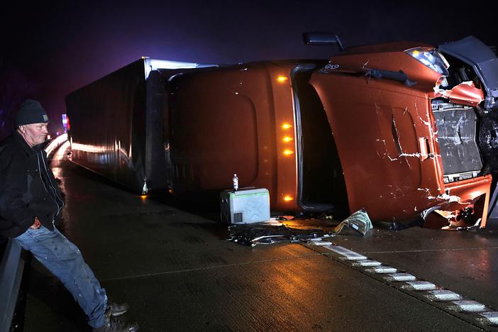 Mark Nelson, of Wis., waits with his tractor-trailer after it overturned during high winds and a possible tornado on Interstate 44 westbound at Villa Ridge, Mo.,  on Friday.