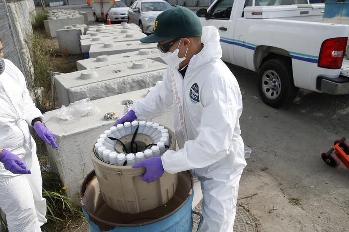 Wastewater sampling plays an increasing role in identifying disease outbreaks. Above: Inspectors in Oakland, Calif., collect samples to send to labs that will try to detect the SARS-CoV-2 virus.
