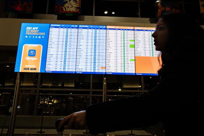 A person walks by an arrival and departure board at Boston's Logan Airport on Dec. 23, 2024.