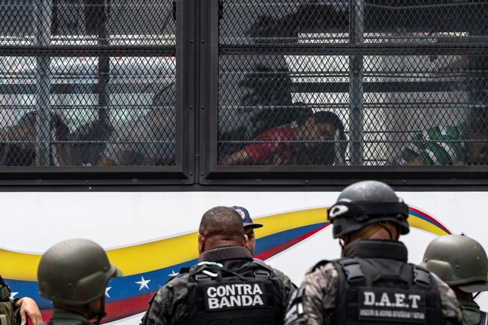 Members of the Bolivarian National Guard (GNB) stand guard as inmates aboard a bus are transferred outside the Tocoron prison in Tocoron, Aragua State, Venezuela, on September 20, 2023.