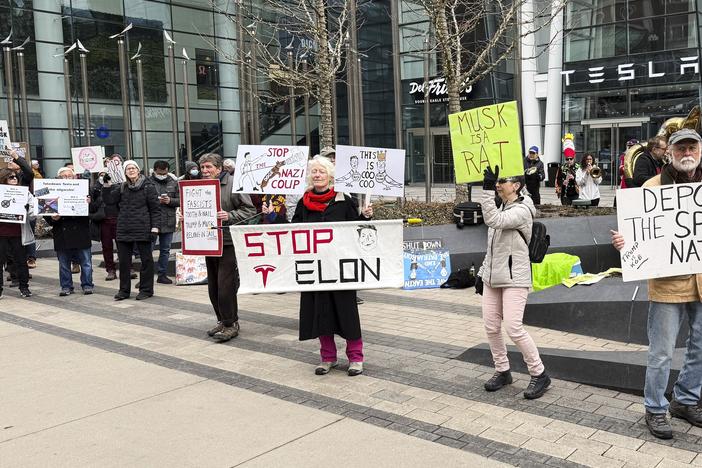 Protesters rally outside a Tesla store in Boston on March 1 against the company's CEO, Elon Musk, who is leading an effort to cut government jobs on behalf of President Trump.