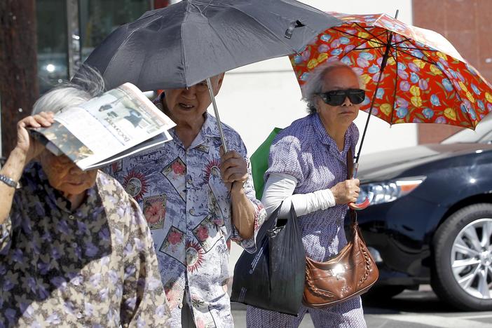 Older people in Los Angeles' Chinatown neighborhood shade themselves from the sun. Exposure to heat can change the way people's genes work, potentially leading to long-term health impacts. Climate change is making heat waves more intense and last longer in many parts of the U.S.