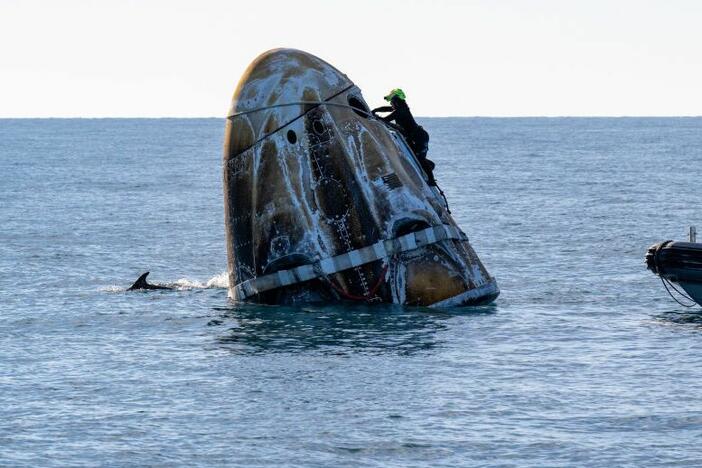 In this handout image provided by NASA, support teams work on the SpaceX Dragon spacecraft shortly after it landed with NASA astronauts Nick Hague, Suni Williams and Butch Wilmore, and Roscosmos cosmonaut Aleksandr Gorbunov onboard on March 18, 2025, off the coast of Florida.