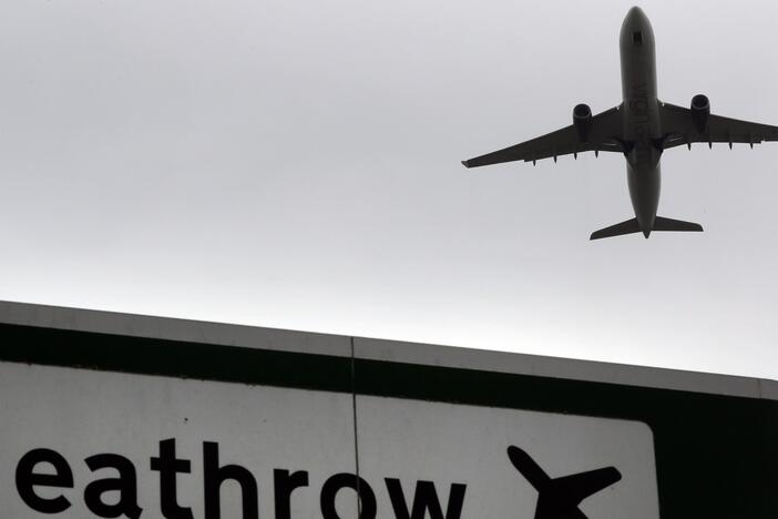 A plane takes off over a road sign near Heathrow Airport in London.
