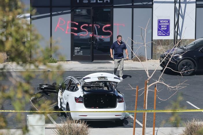 An investigator looks over the scene at a Tesla Collision Center after a person used incendiary devices to set several vehicles on fire on Tuesday in Las Vegas. The Las Vegas Metropolitan Police Department said that five Teslas were damaged and believe that the suspect fired three rounds from a firearm at the vehicles and spray painted the word "RESIST" on the entrance.