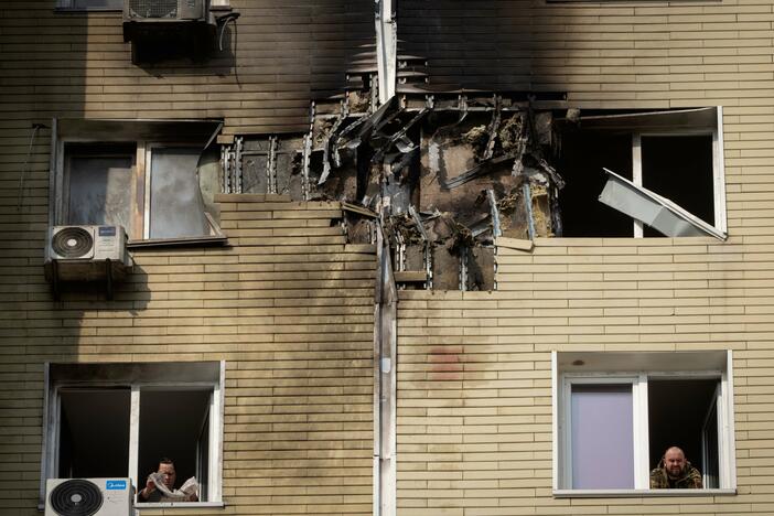 A resident watches as his neighbor cleans up a damaged apartment after a Russian drone attack in Kyiv, Ukraine, March 23.
