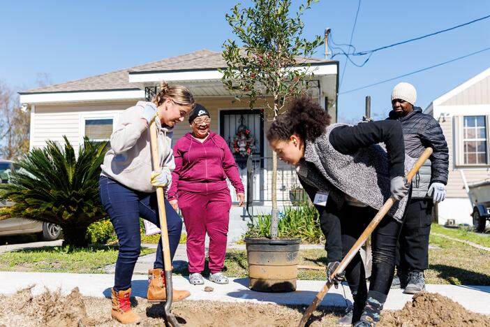 Volunteers Olly De Almeida (left), Jordan Bordenave (right) and Rosemary White (far right) plant a tree in front of Tribble Condor's (center) house in New Orleans' Lower 9th Ward. The project was funded by a federal grant terminated in February.