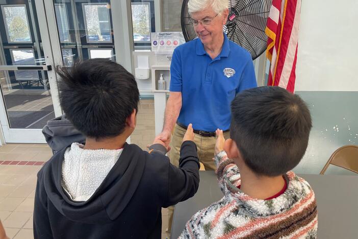 Fourth-graders line up to shake hands with Dennis Cuddy, one of the volunteers with Grandpas United, in White Plains, N.Y.